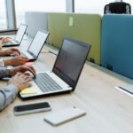 Colleagues working diligently at shared desks with laptops in a modern office space.